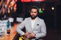 Handsome young man drinking cocktail at bar counter, wearing business suit. Royalty Free Stock Photo