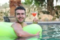 Handsome young man drinking a cocktail while relaxing in a swimming pool Royalty Free Stock Photo