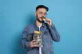 Handsome young man eating tasty potato chips on light blue background Royalty Free Stock Photo