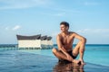 Handsome young man at the edge of infinity swimming pool at the tropical island luxury resort Royalty Free Stock Photo