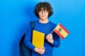 Handsome young man exchange student holding spanish flag relaxed with serious expression on face Royalty Free Stock Photo