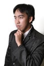 Handsome young man in full suit adjusting his necktie and looking at camera while standing against white background. Royalty Free Stock Photo