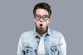 Handsome young man with funny glasses joking and making funny face over gray background. Royalty Free Stock Photo