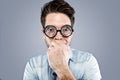 Handsome young man with funny glasses joking and making funny face over gray background.