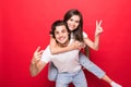 Handsome young man giving piggy back to his girlfriend on red background Royalty Free Stock Photo