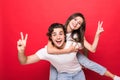 Handsome young man giving piggy back to his girlfriend on red background Royalty Free Stock Photo