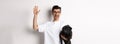 Handsome young man in glasses holding his black pug and waving hand, guy saying hello while carry dog with one arm Royalty Free Stock Photo