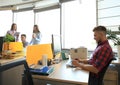 Handsome young man glasses holding smart phone and looking at it while sitting at his working place. Royalty Free Stock Photo