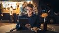 Handsome Young Man in Glasses is Using a Tablet while Sitting at a Table in a Outdoors Street Food Royalty Free Stock Photo