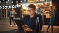 Handsome Young Man in Glasses is Using a Tablet while Sitting at a Table in a Outdoors Street Food Royalty Free Stock Photo