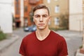 Handsome young man with hair in a red shirt stands