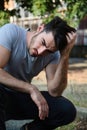 Handsome young man with hand in hair crouching in park Royalty Free Stock Photo