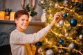 Smiling guy decorating Christmas tree. Royalty Free Stock Photo