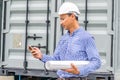 Handsome young man in hardhat holding blueprint and using mobile phone Royalty Free Stock Photo