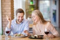 Handsome young man and his beloved woman having festive dinner with wine and yummy food at restaurant Royalty Free Stock Photo