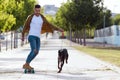 Handsome young man with his dog skateboarding in the park. Royalty Free Stock Photo