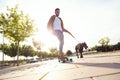 Handsome young man with his dog skateboarding in the park. Royalty Free Stock Photo