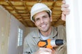handsome young man holding electric drill and smiling at camera Royalty Free Stock Photo