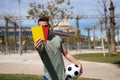 Handsome young man holding a football in his hand while showing red and yellow card to camera as if he were a football referee. Royalty Free Stock Photo
