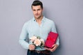 Handsome young man holding gift box and flowers Royalty Free Stock Photo