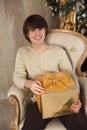 Handsome young man holding gift box sitting on armchair in beige Royalty Free Stock Photo