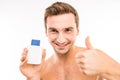 Handsome young man holding lotion after shave showing thumb up Royalty Free Stock Photo