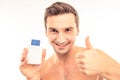 Handsome young man holding lotion after shave showing thumb up Royalty Free Stock Photo