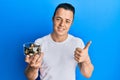 Handsome young man holding raw hazelnuts smiling happy and positive, thumb up doing excellent and approval sign Royalty Free Stock Photo