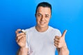 Handsome young man holding raw oyster smiling happy and positive, thumb up doing excellent and approval sign Royalty Free Stock Photo