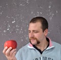 Handsome young man is holding a red apple standing