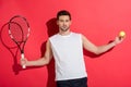 handsome young man holding tennis racket with ball and looking at camera Royalty Free Stock Photo