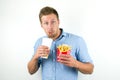 Handsome young man holds soda in papper cup and fries from fast food restaurant looks surprised on isolated white Royalty Free Stock Photo