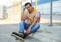 Handsome young man with inline roller skates sitting on curb Royalty Free Stock Photo