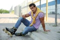 Handsome young  with inline roller skates sitting on curb outdoors Royalty Free Stock Photo