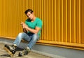 Handsome young man with inline roller skates sitting near yellow building Royalty Free Stock Photo