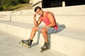 Handsome young man with inline roller skates sitting on stairs Royalty Free Stock Photo