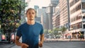 Handsome Young Man is Jogging on a Street of a Big City Center. Male is Running in Blue T-Shirt, Royalty Free Stock Photo