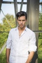 Handsome young man leaning against metal electricity trellis