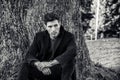 Handsome young man leaning against tree