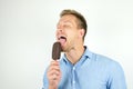 Handsome young man licking chololate ice-cream on isolated white background