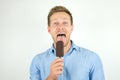 Handsome young man licks tasty chololate ice-cream on isolated white background