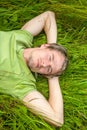 A handsome young man lies on green grass. Royalty Free Stock Photo