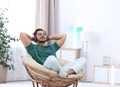 Handsome young man listening music in armchair at home. Royalty Free Stock Photo