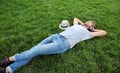 Handsome young man listening to music on green grass in park Royalty Free Stock Photo