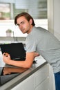 Young man looking back at the camera while holding a credit card and using a laptop. Online shopping and payment concept Royalty Free Stock Photo