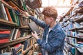 Portrait of a student who browses books from public library shelves. Search the book in the library Royalty Free Stock Photo
