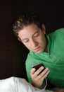 Handsome young man looking at cell phone at night in bed Royalty Free Stock Photo