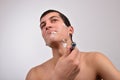 Handsome young man with lots of shaving cream on his face preparing to shave with razor