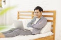 Handsome young man lying in bed and using laptop to watch movies Royalty Free Stock Photo