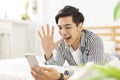 Handsome young man lying on the bed and using a mobile phone to make a video call, and waving to the screen to greet each other Royalty Free Stock Photo